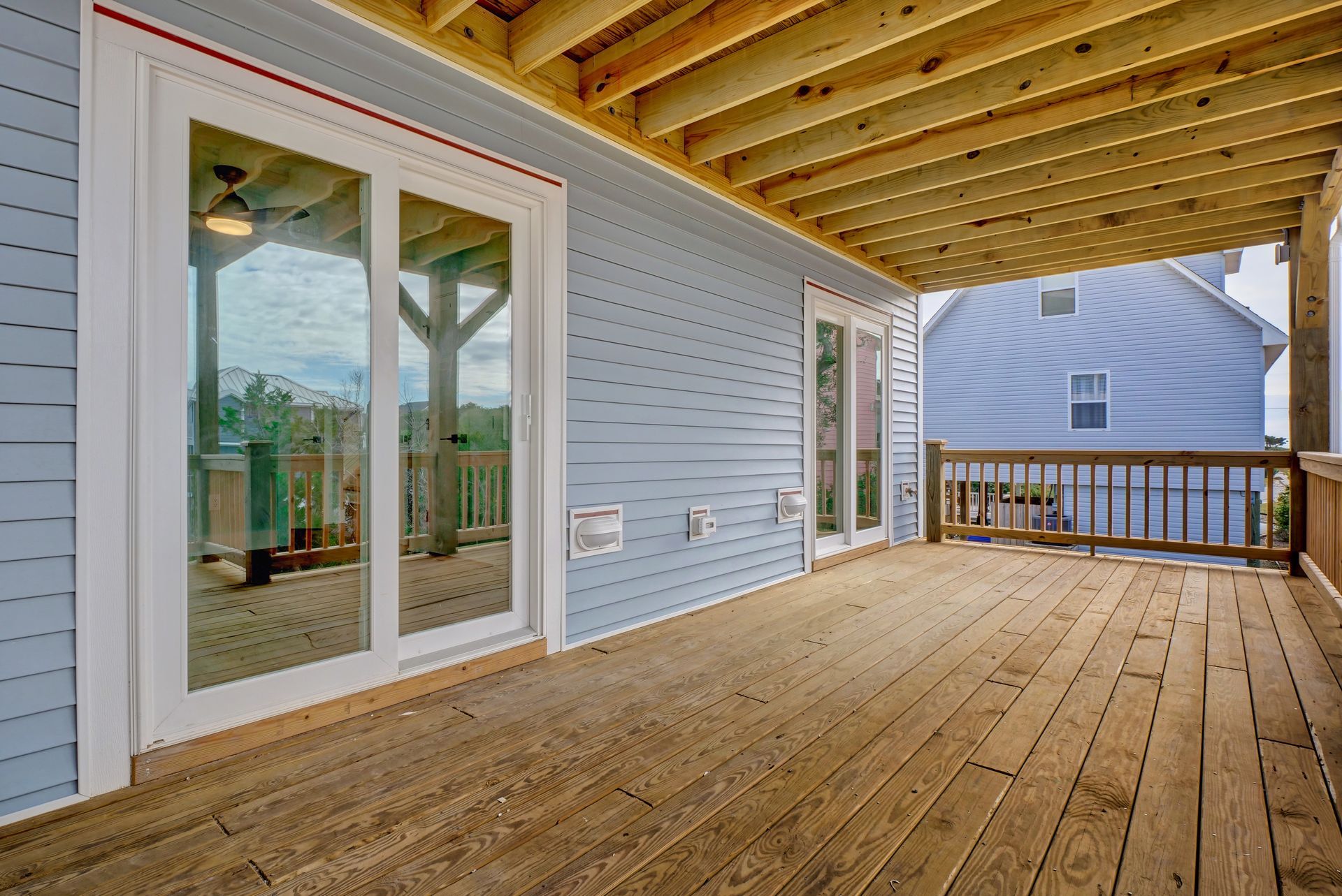 A large wooden deck with sliding glass doors and a ceiling fan.