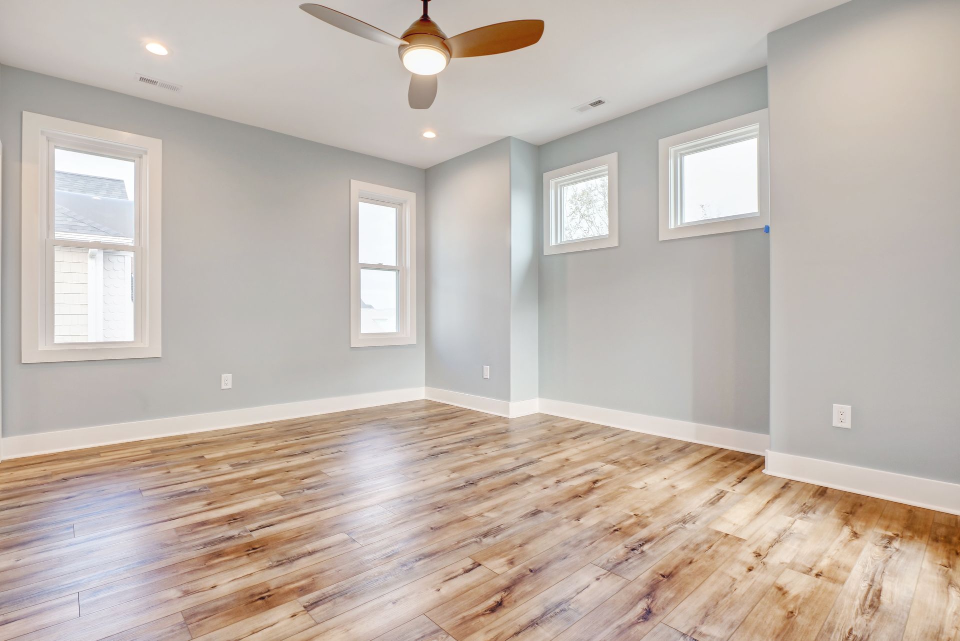 An empty room with hardwood floors and a ceiling fan.