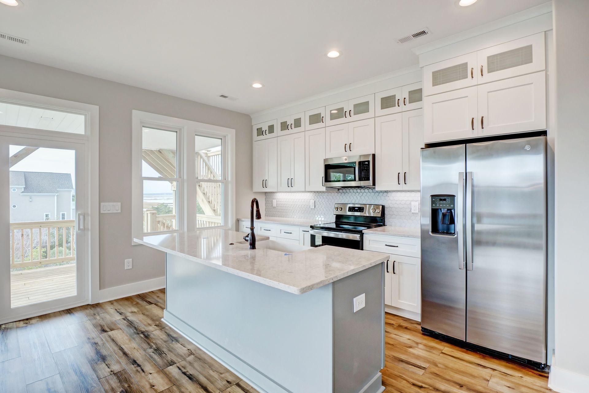 A kitchen with white cabinets , stainless steel appliances , and a large island.