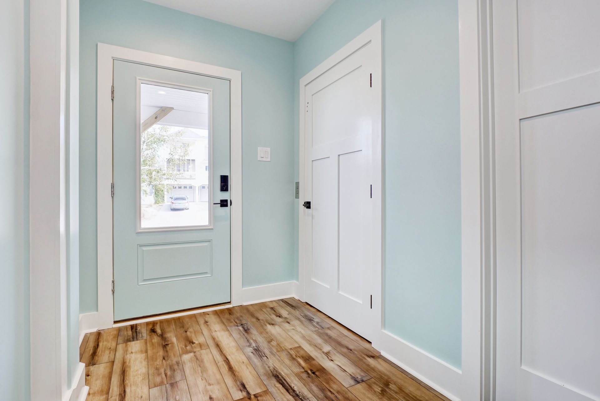 A hallway with hardwood floors and a blue door.