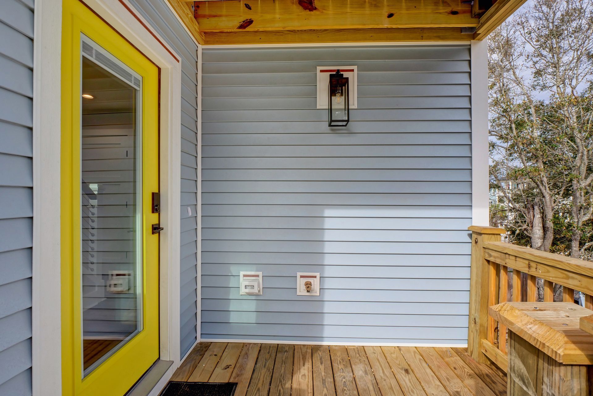 A blue house with a yellow door and a wooden deck.