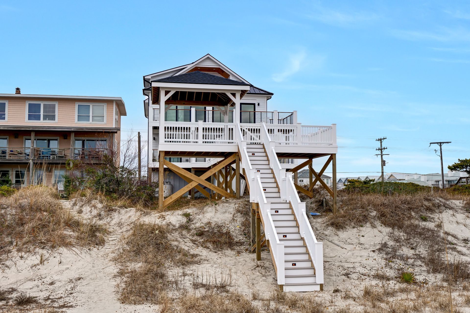 A house on stilts on the beach with stairs leading up to it.