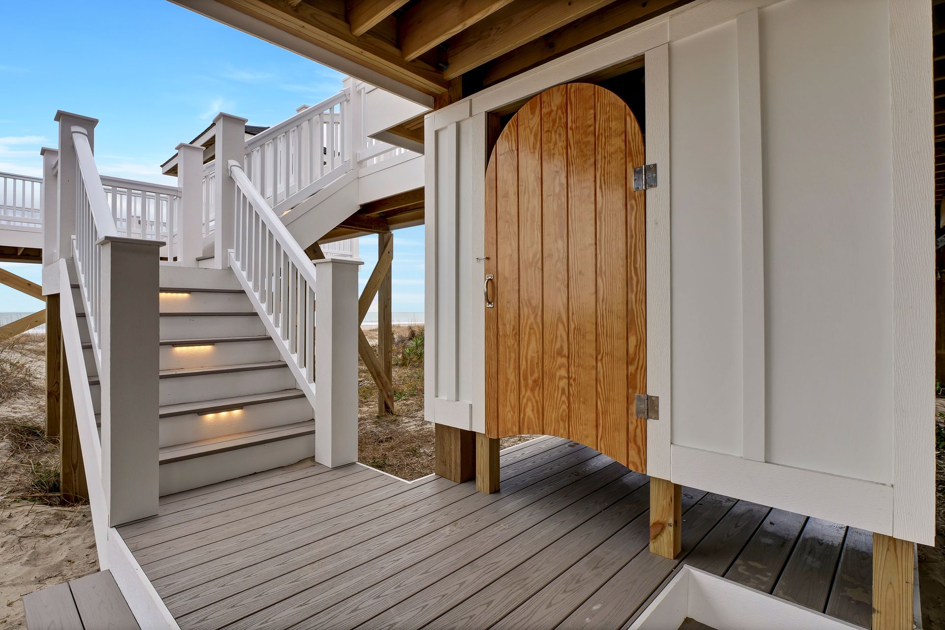 A white house with a wooden door and stairs leading up to it.