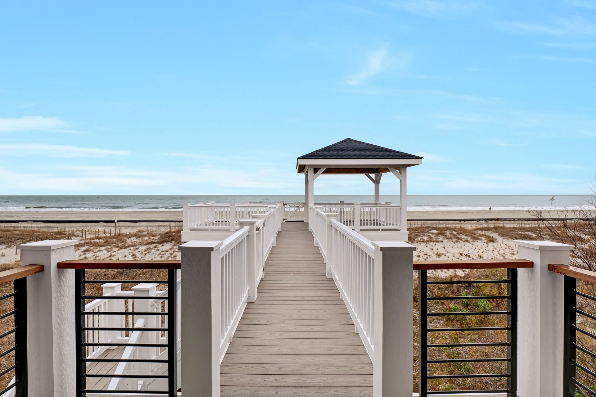 A wooden walkway leading to a gazebo on the beach.