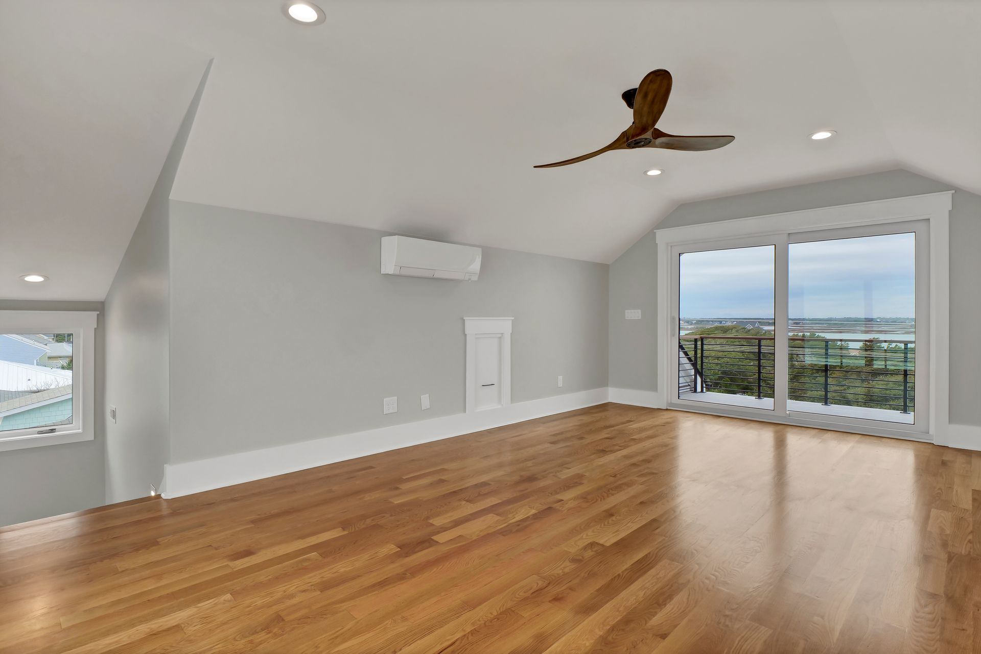 An empty living room with hardwood floors and a ceiling fan.