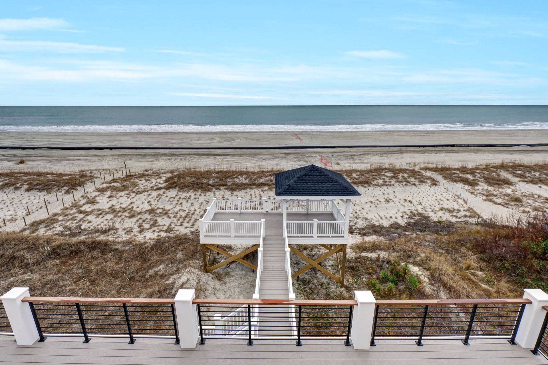 There is a gazebo on the beach with a view of the ocean.