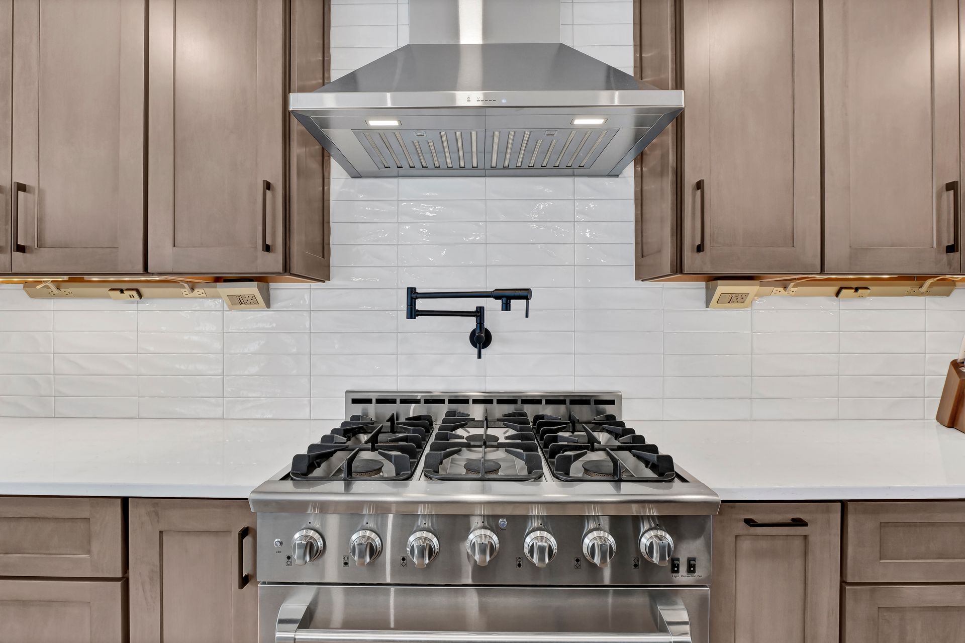 A kitchen with a stove and a hood above it.