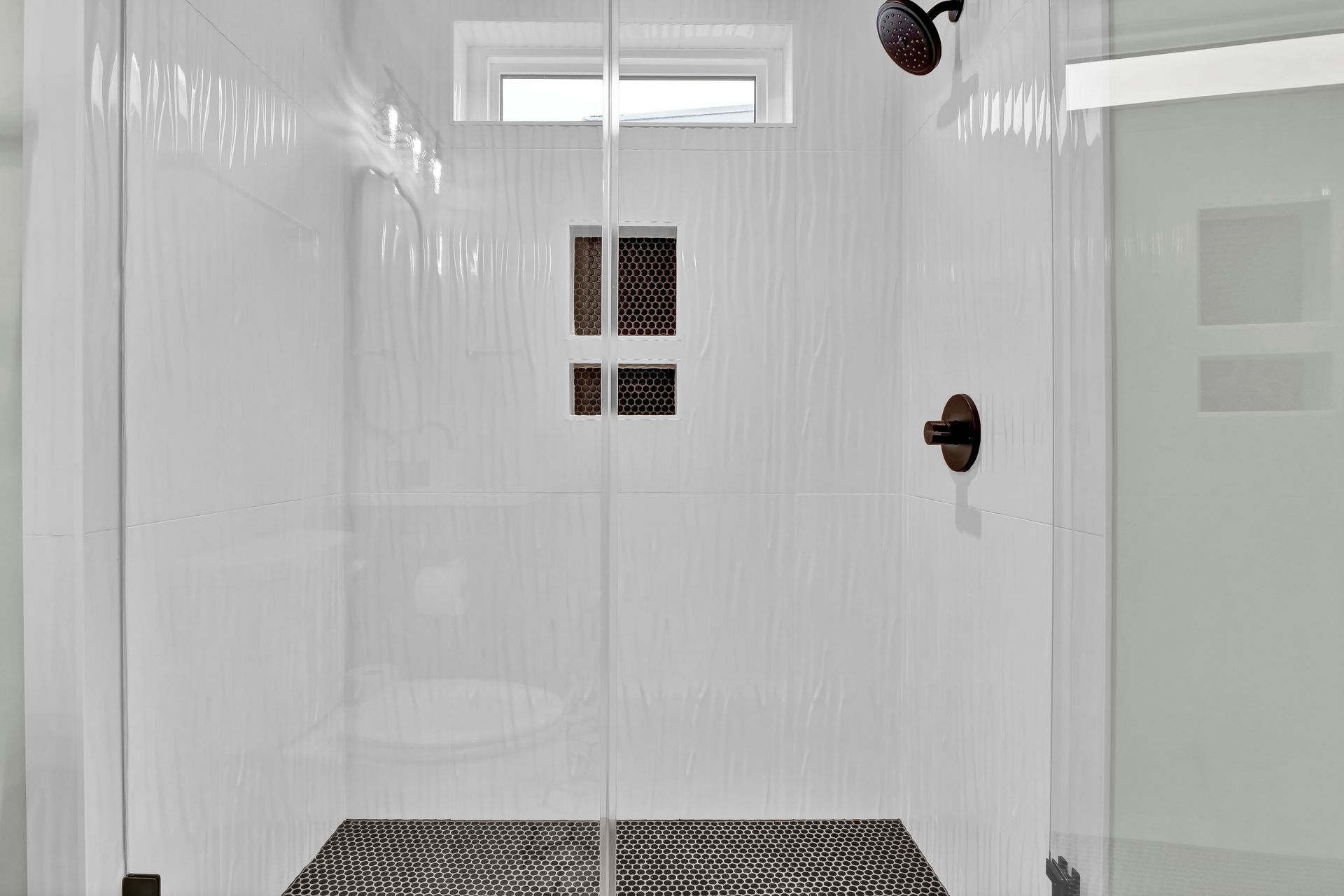 A bathroom with a walk in shower with a glass door.