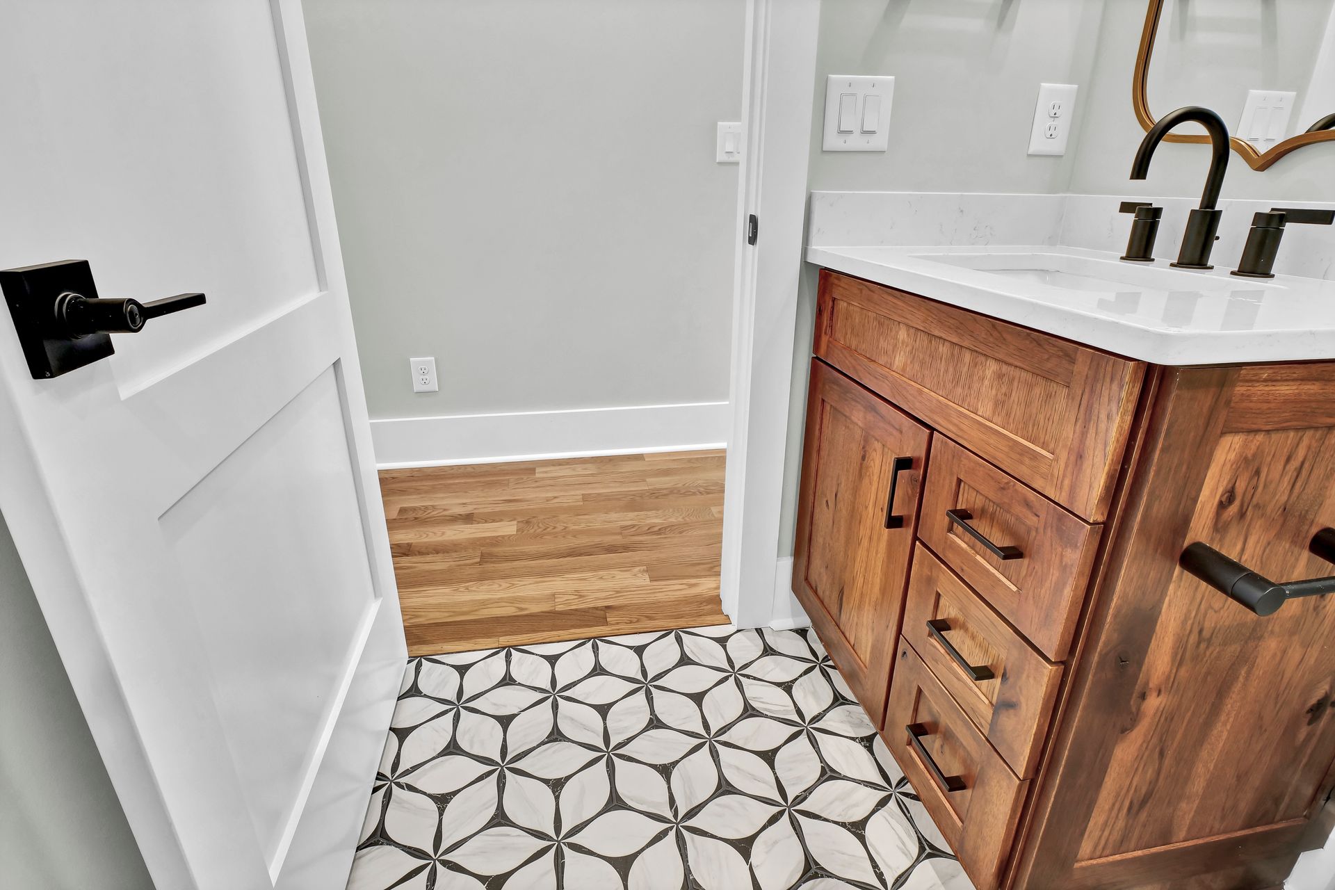 A bathroom with a wooden vanity and a black and white tile floor.