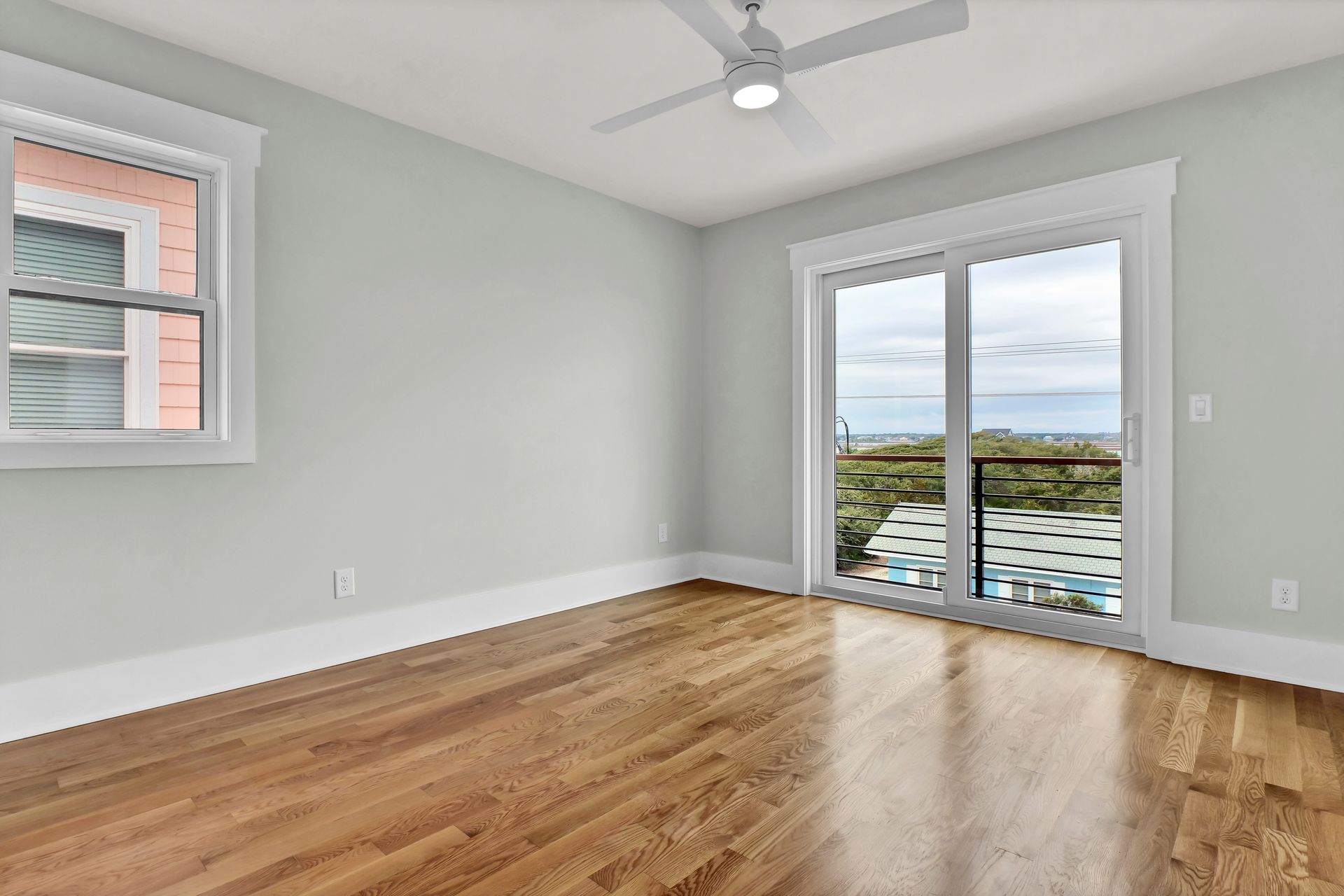 An empty room with hardwood floors and a ceiling fan