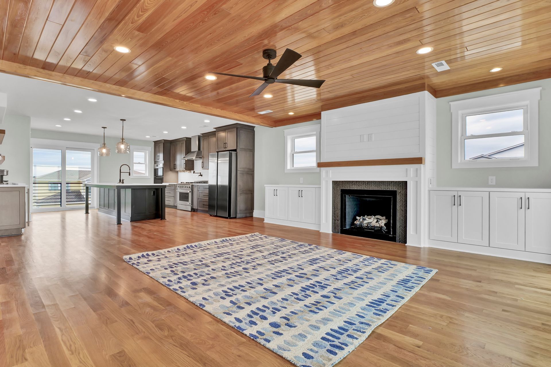 A living room with hardwood floors , a fireplace , a rug and a ceiling fan.