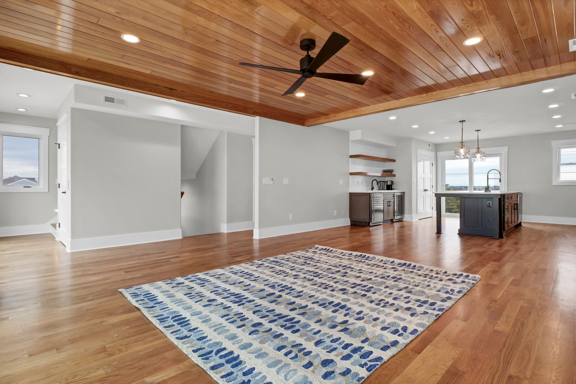 A living room with hardwood floors , a rug and a ceiling fan.