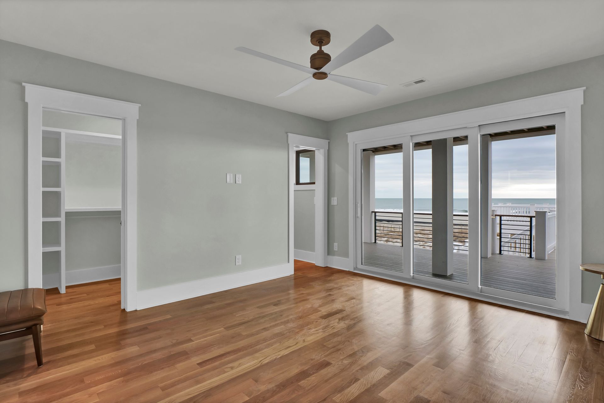 An empty room with hardwood floors and a ceiling fan.