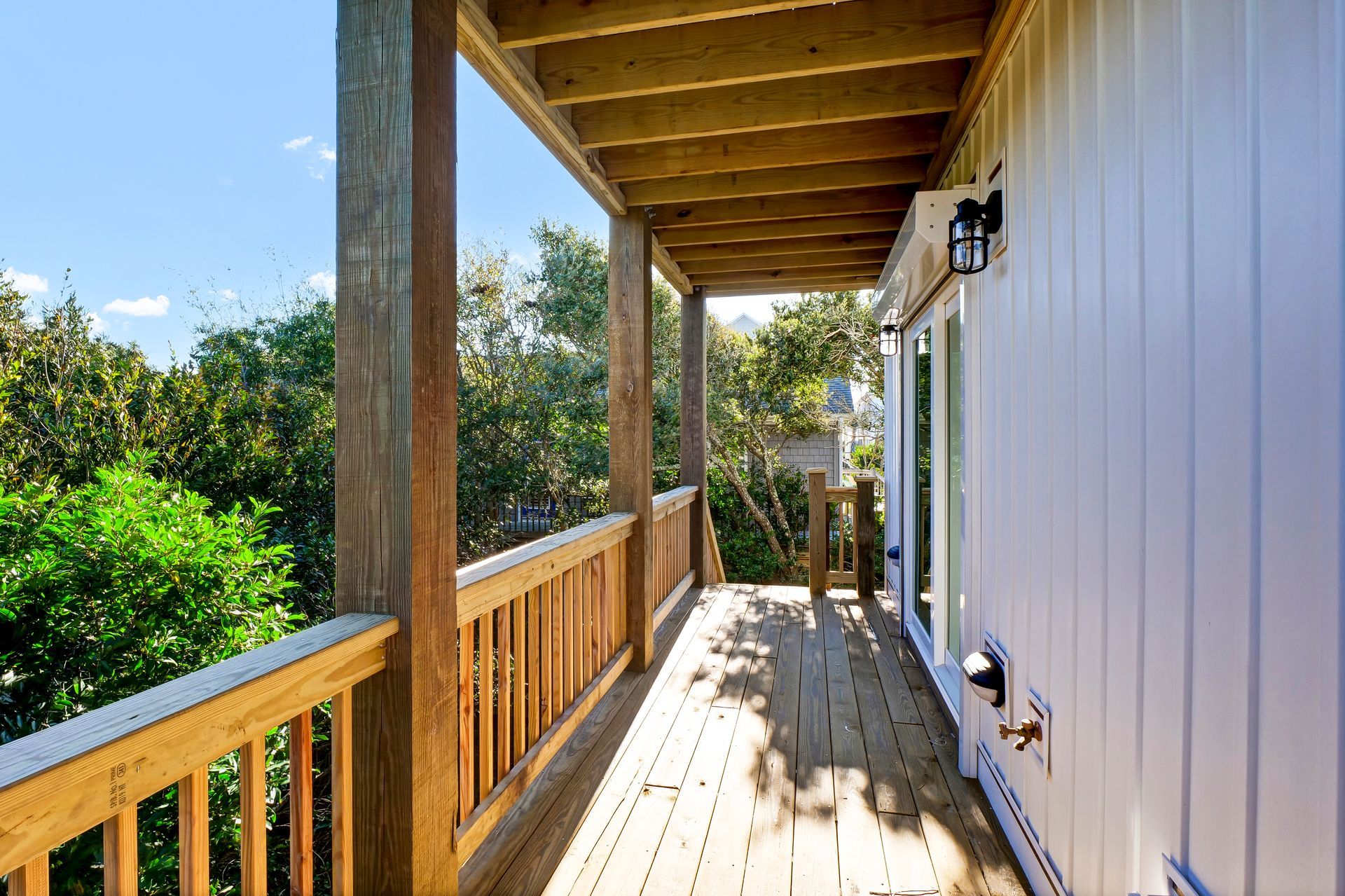 A white house with a wooden deck and a wooden railing.