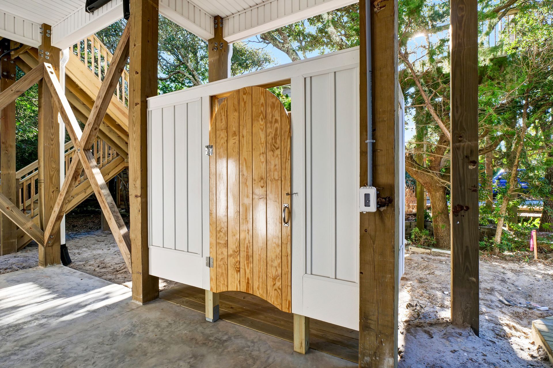 A wooden shed with a white door and a staircase in the background.