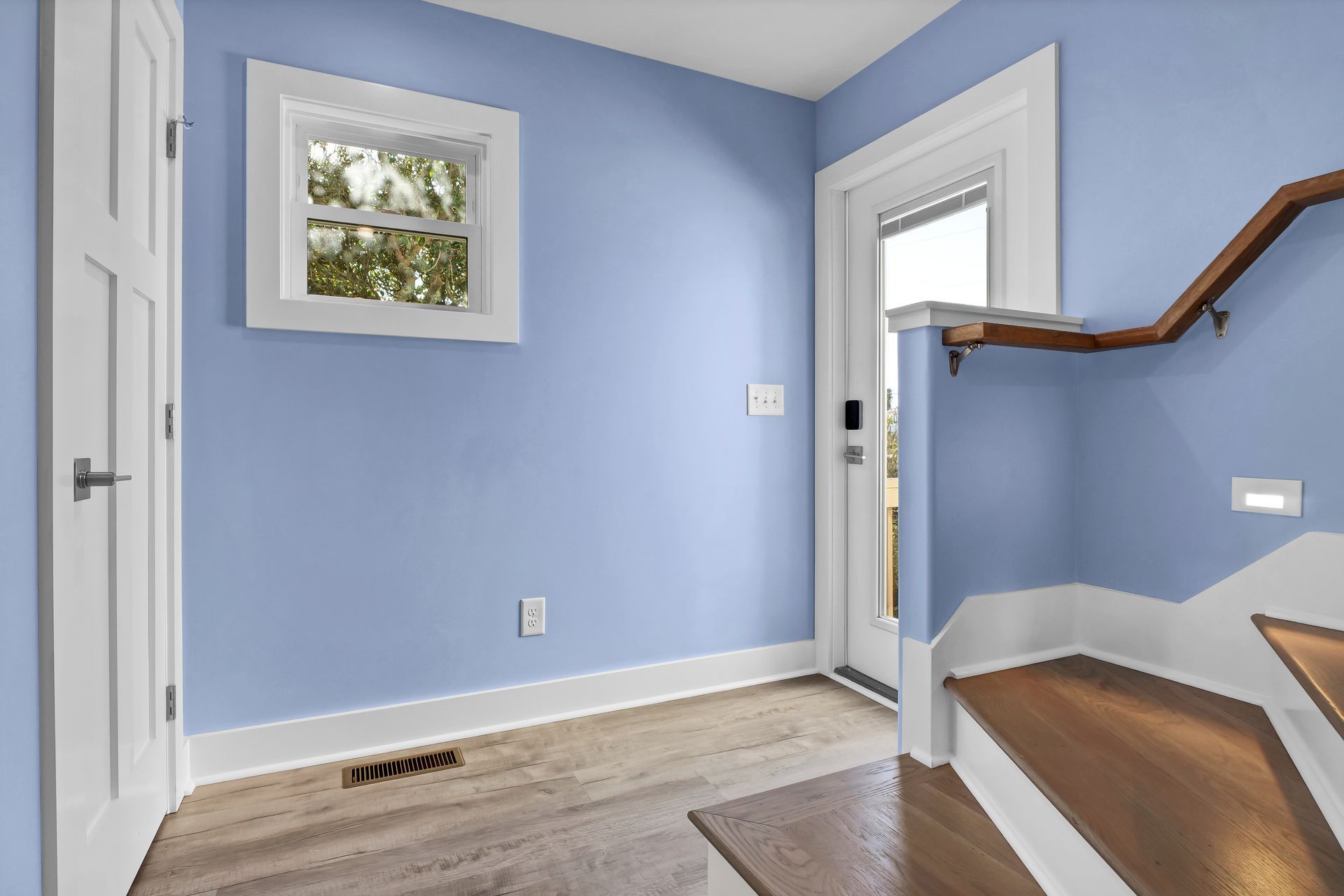 A room with blue walls and wooden stairs and a window.