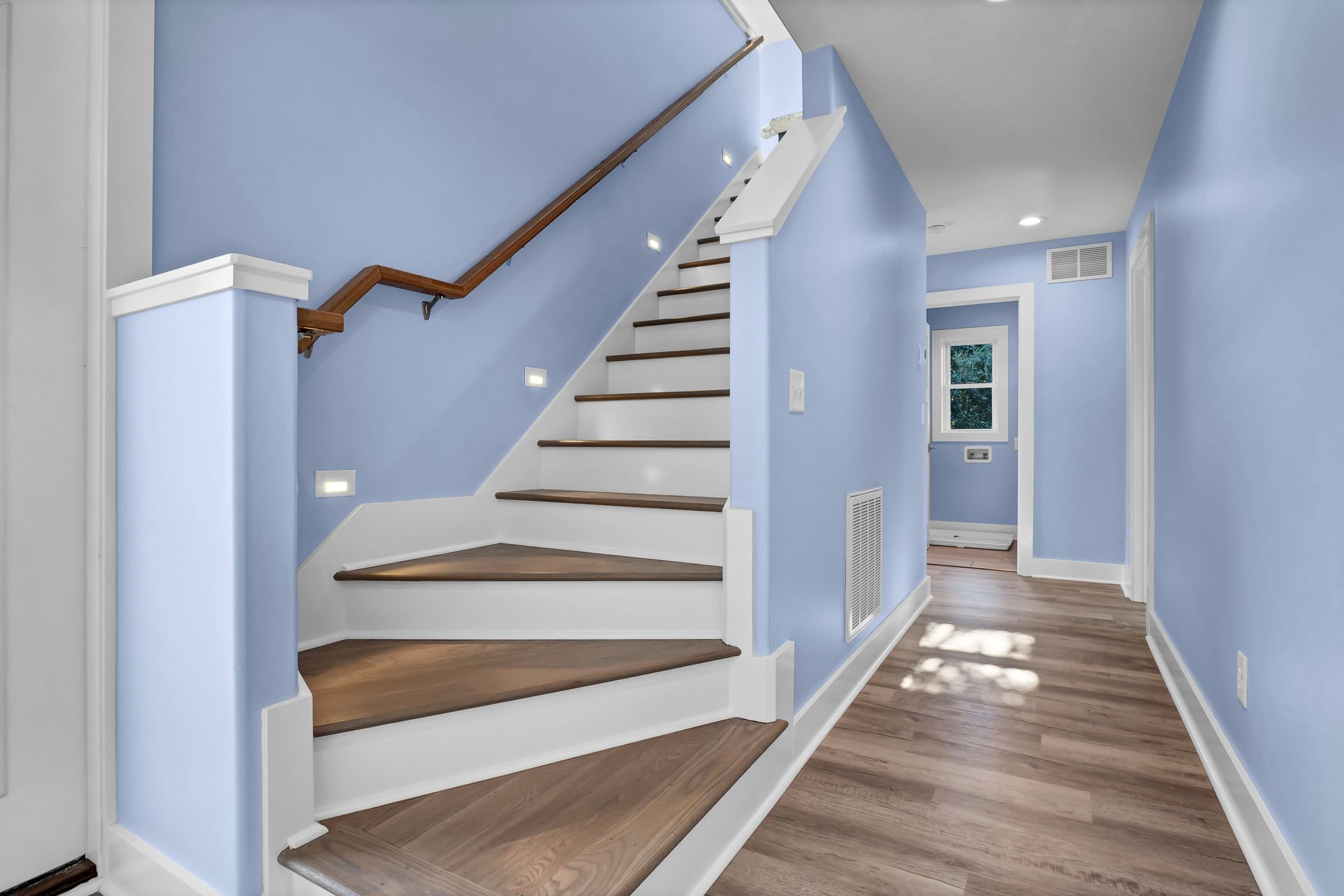 A hallway with blue walls and white stairs