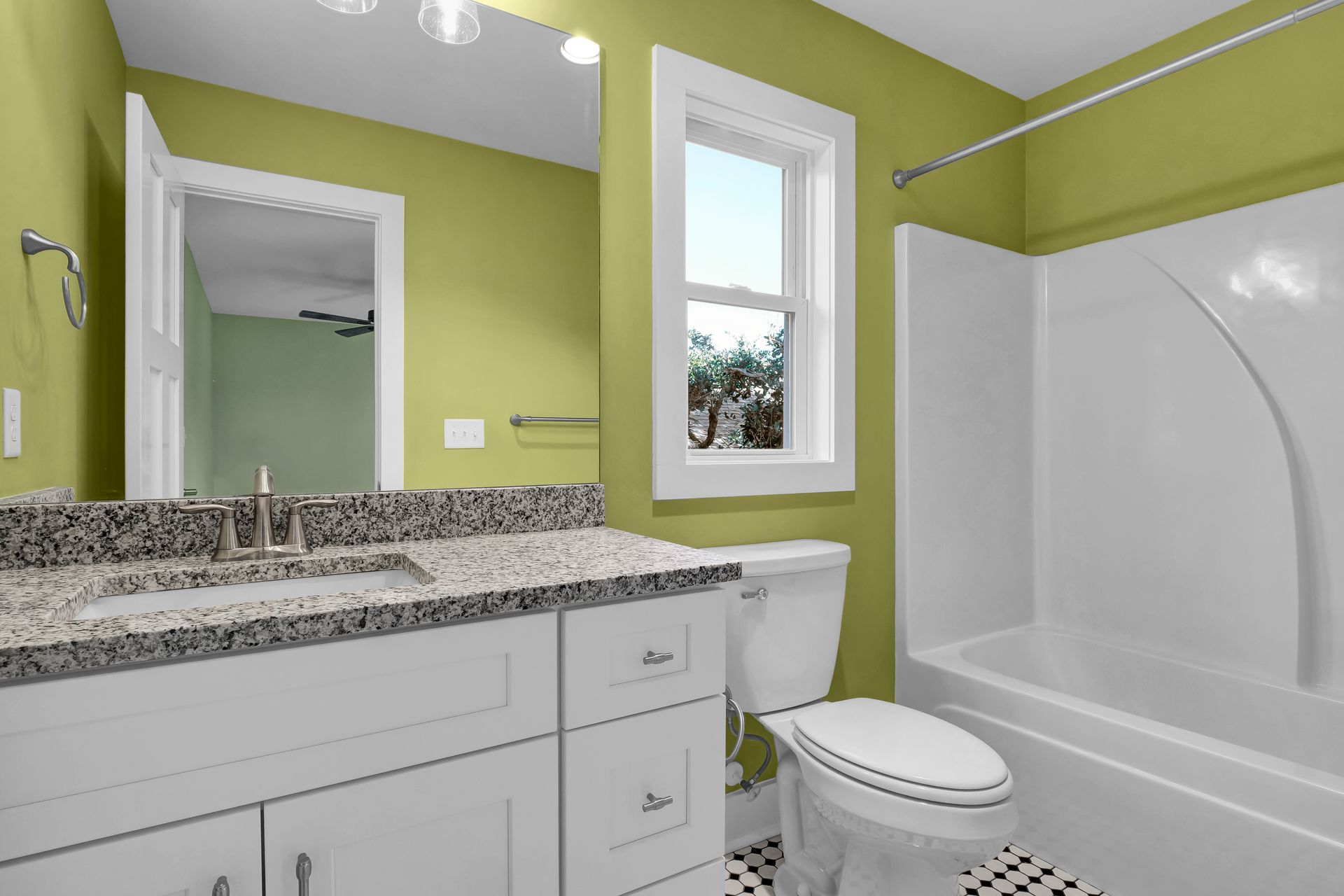 A bathroom with green walls , a toilet , sink , and bathtub.