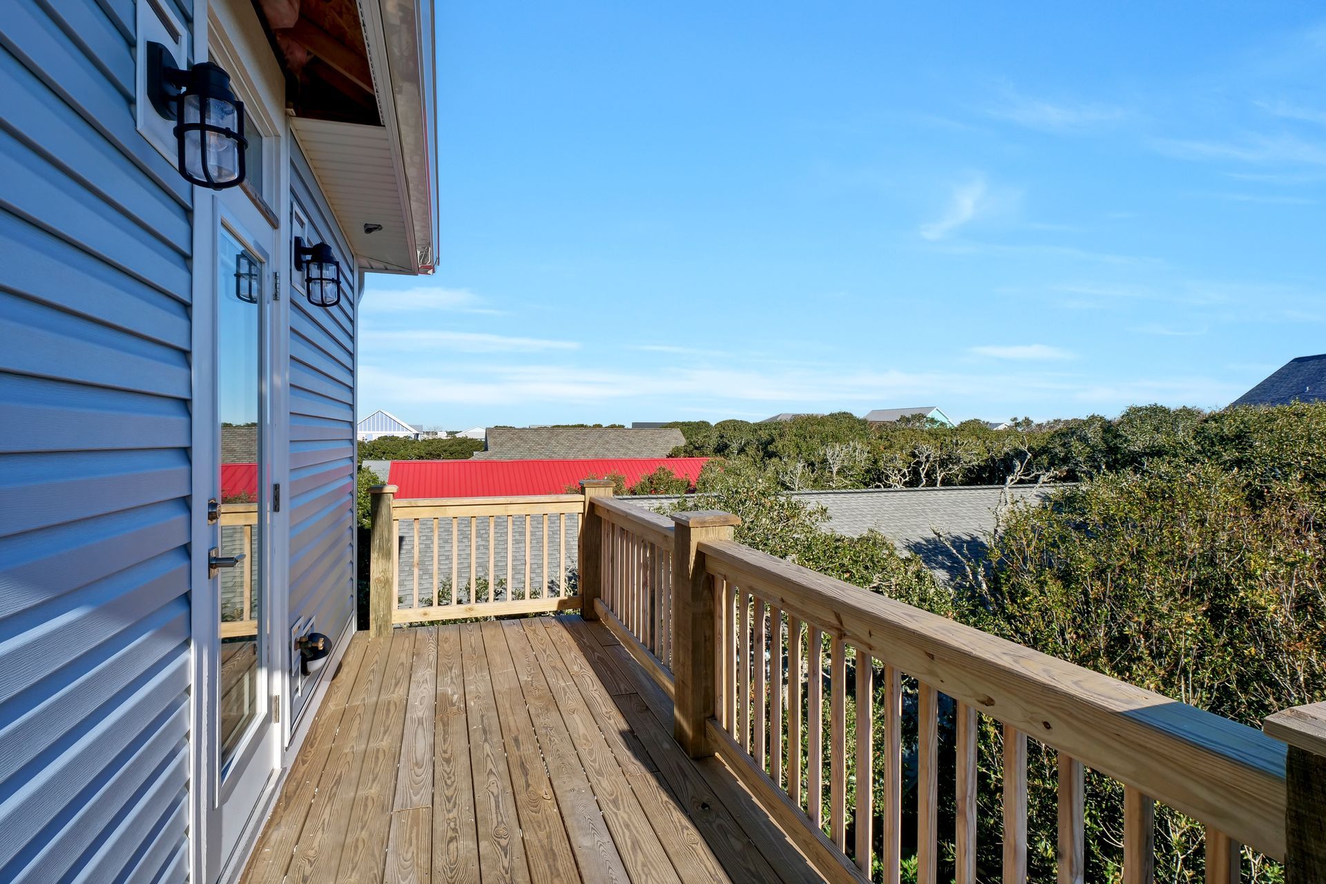 A wooden deck with a railing and a blue house in the background.