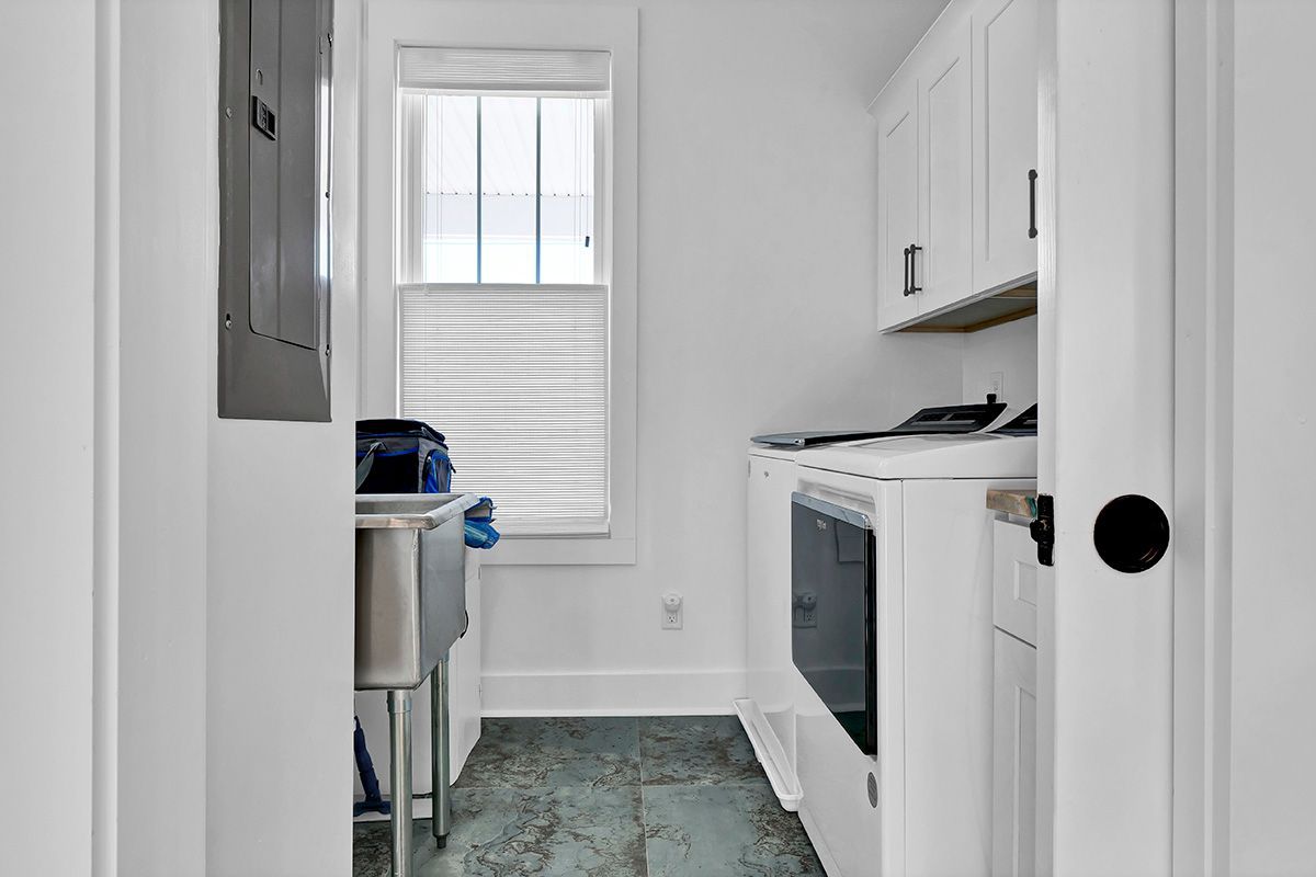 A kitchen with white cabinets, a stove, a sink, and a window