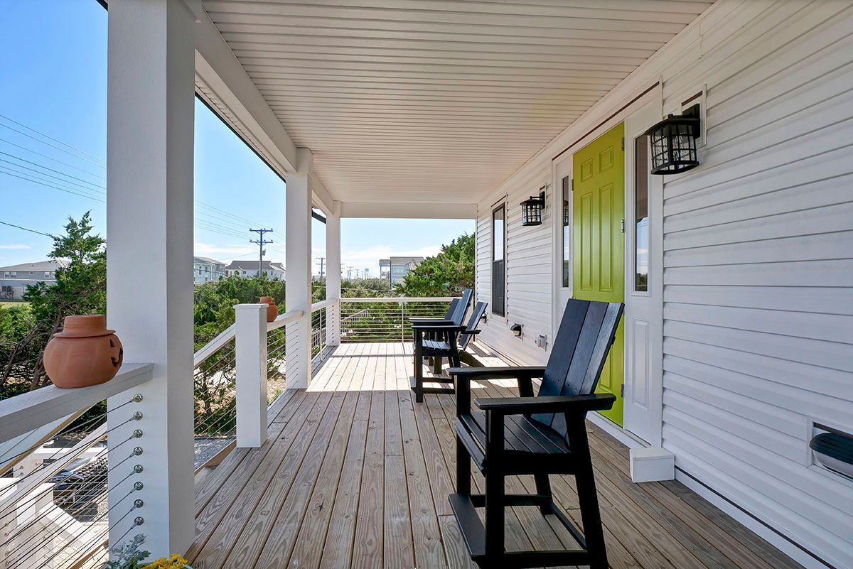 A porch with chairs and a green door