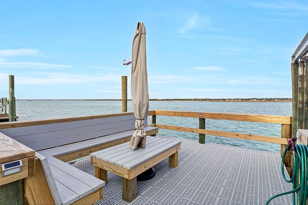 A dock with a table and umbrella on it overlooking the ocean
