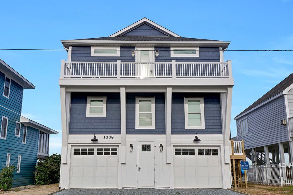 A large blue and white house with two garages and a balcony