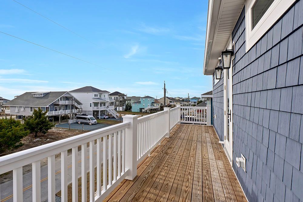 A large deck with a white railing on the side of the house