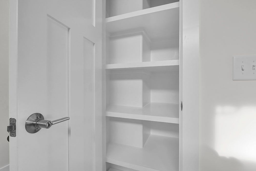 A white closet with shelves and a door in a bathroom