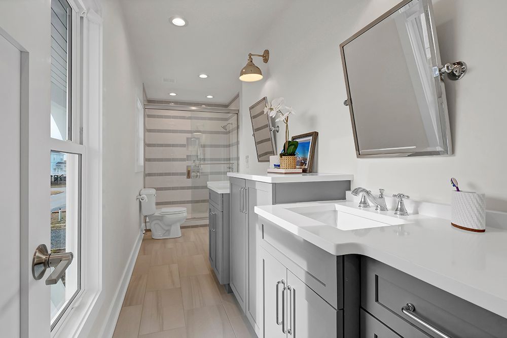 A bathroom with a sink, toilet, mirror, and walk-in shower