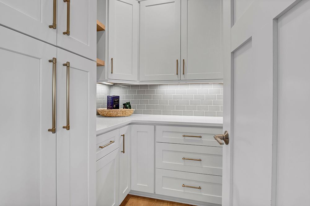A pantry in the kitchen with white cabinets and drawers
