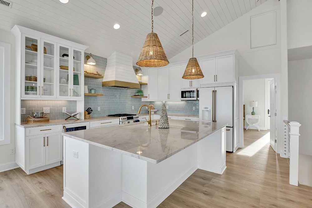 A kitchen with white cabinets, granite countertops, stainless steel appliances, and a large island