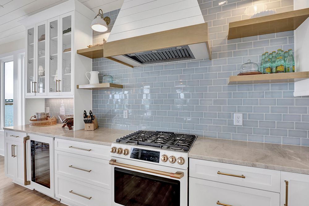A kitchen with white cabinets, a stove-top oven, and a hood