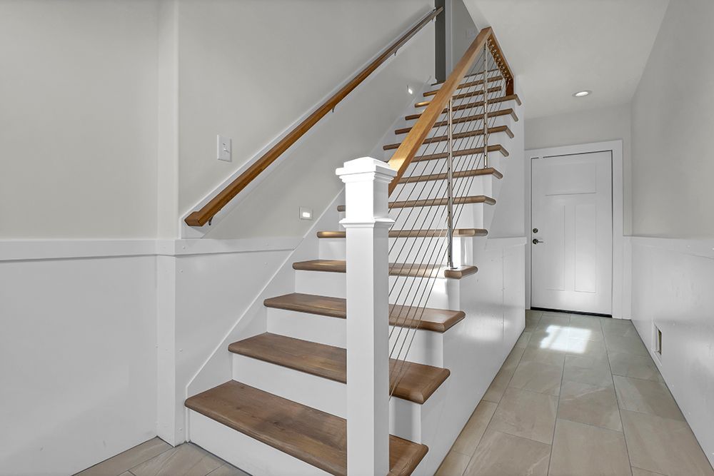 A white staircase with wooden steps and a glass railing