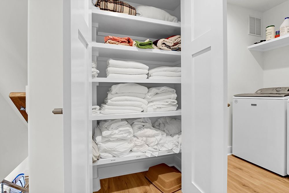 A laundry room with a closet filled with towels and a washer and dryer