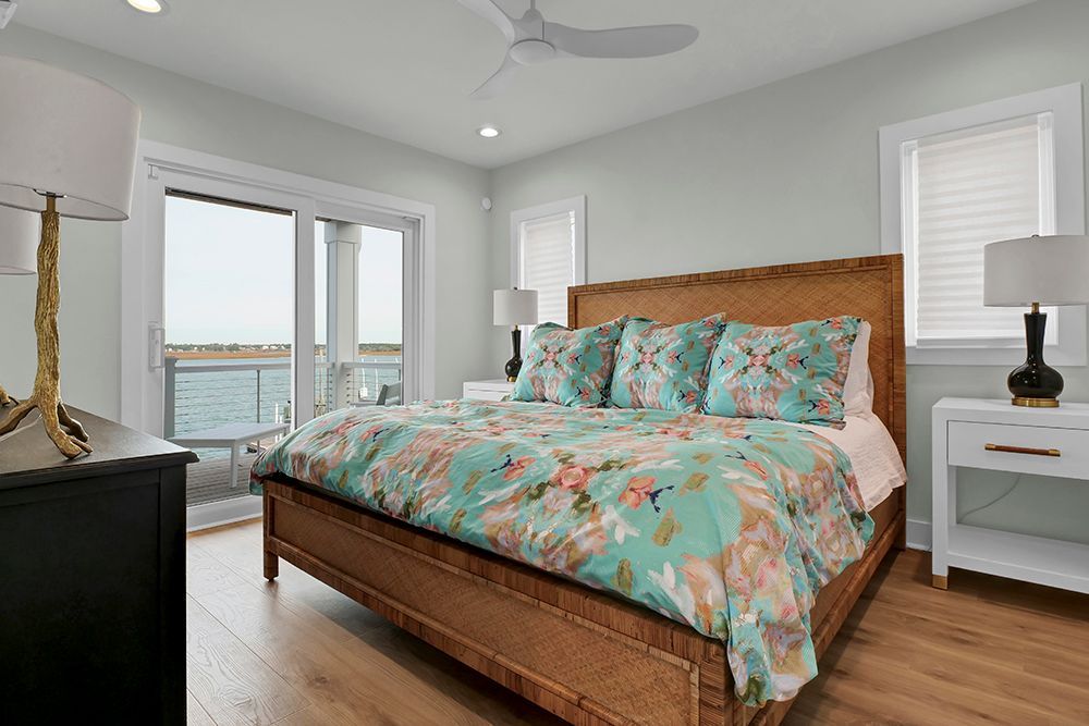 A bedroom with a king-size bed, sliding glass doors, lamps, and a ceiling fan