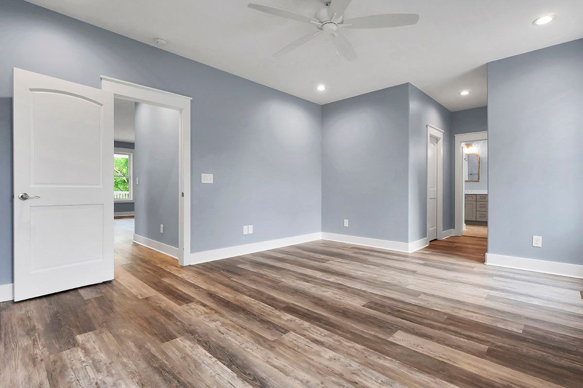 A large empty room with hardwood floors and a ceiling fan
