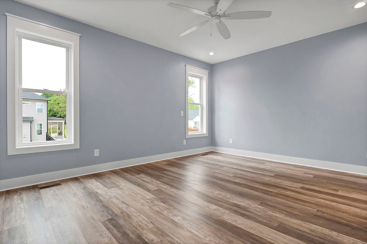 An empty room with hardwood floors and a ceiling fan