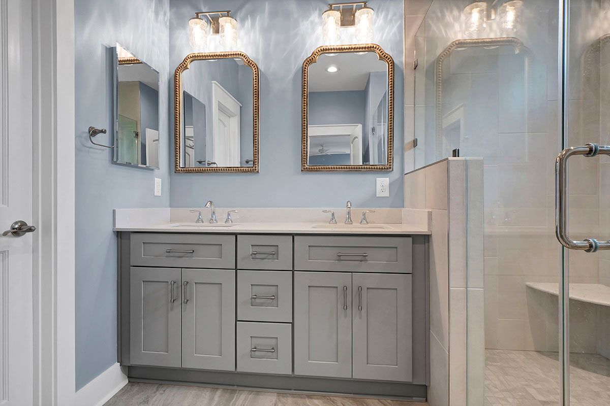 A bathroom with two sinks, two mirrors, and a walk-in shower