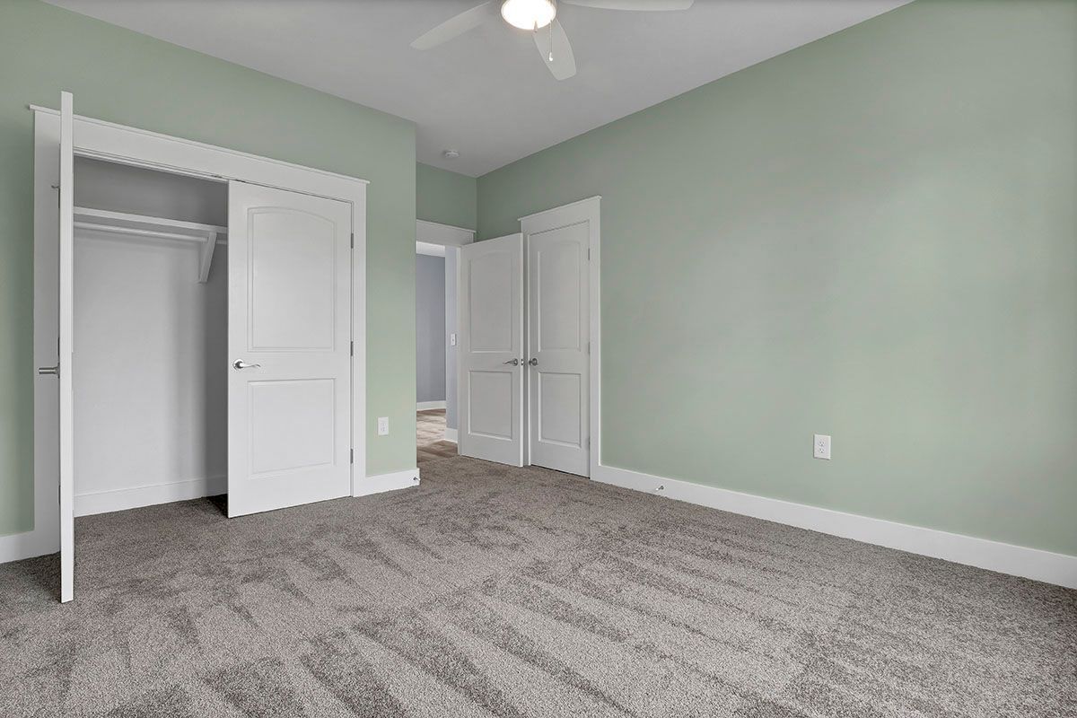 An empty bedroom with green walls and a ceiling fan