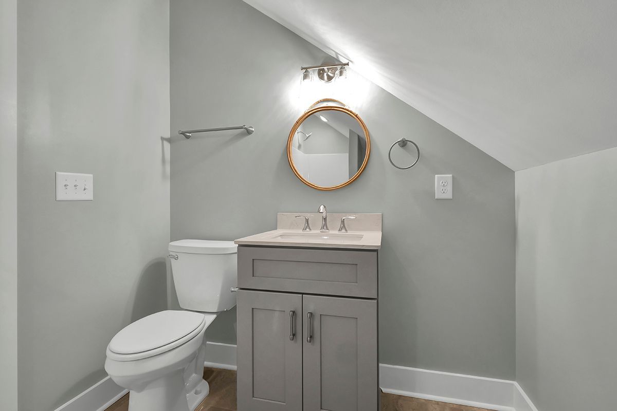 A bathroom with a toilet, sink, and mirror