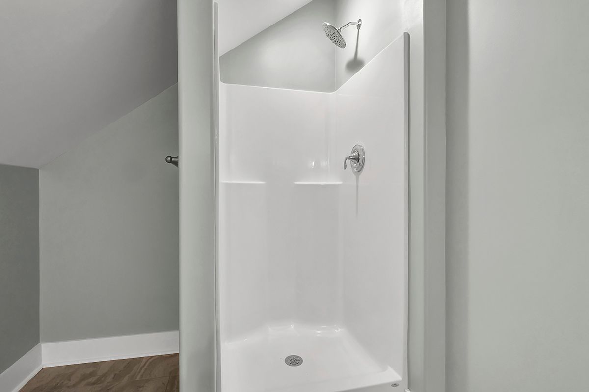 A white shower stall with a shower head in a bathroom
