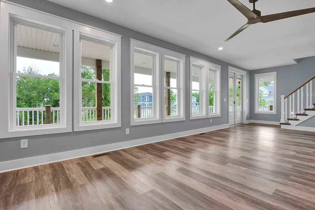 An empty living room with hardwood floors and a ceiling fan
