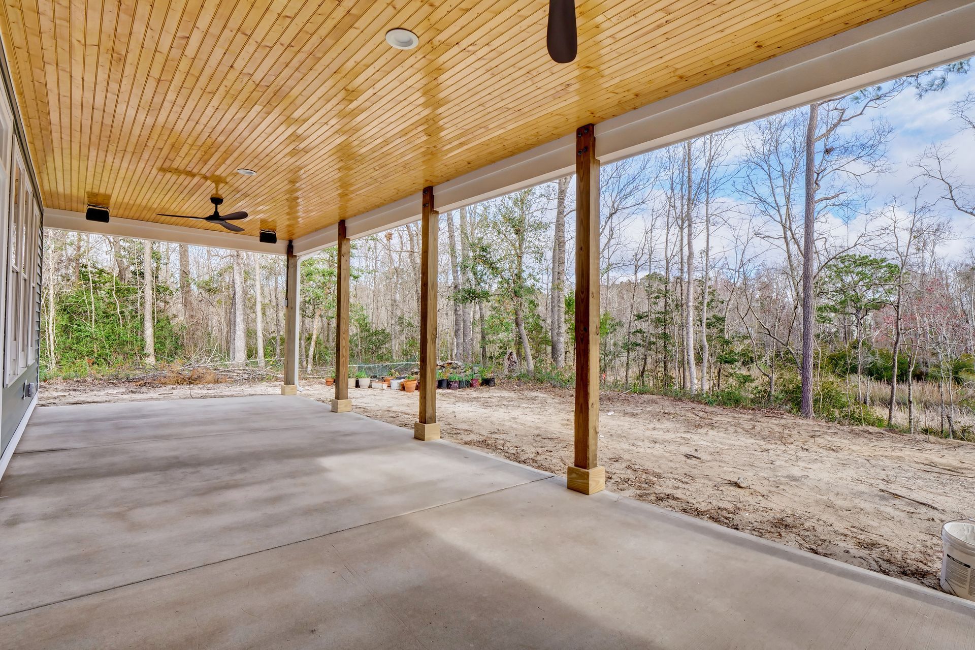 A large covered porch with a wooden ceiling and a ceiling fan.