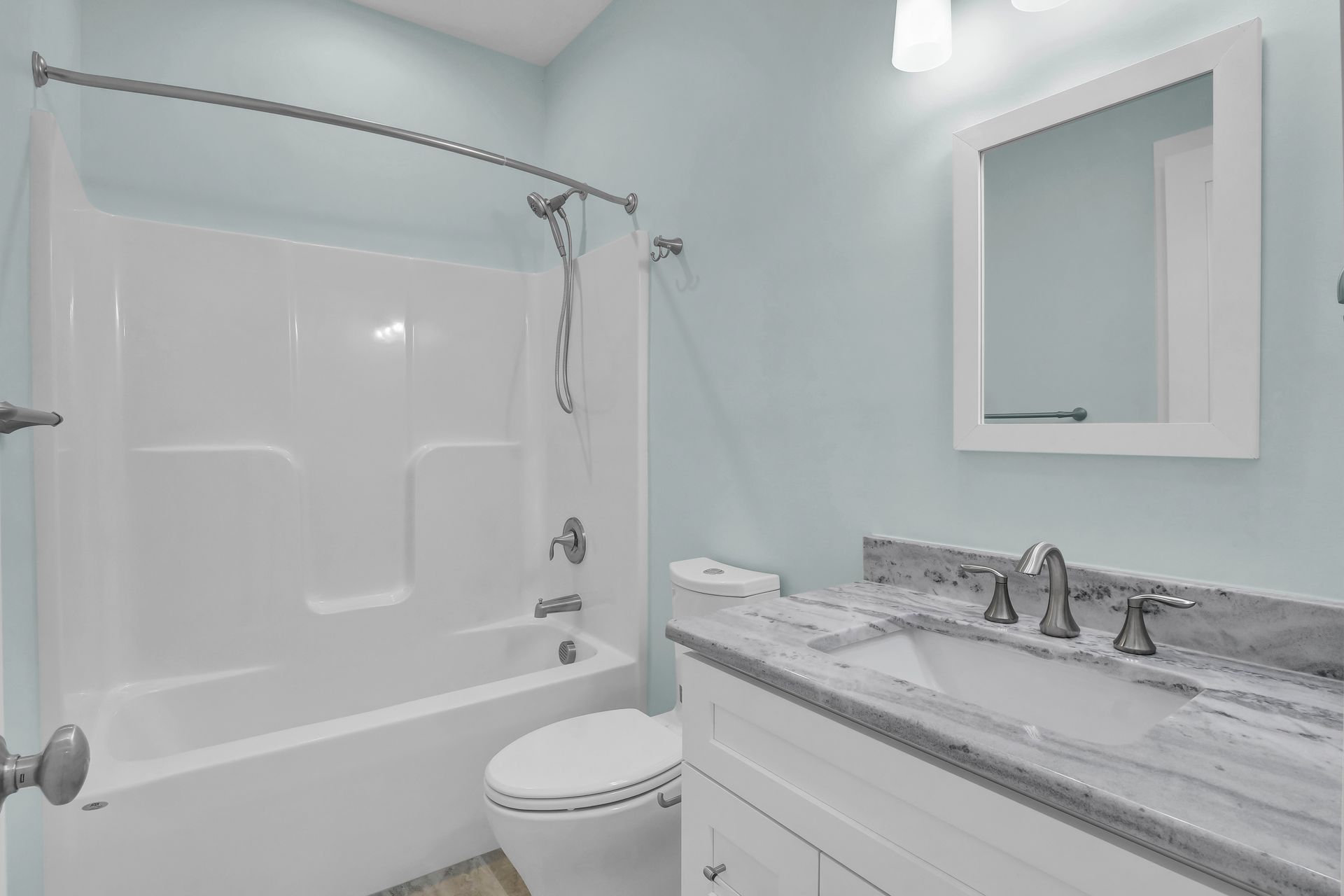 A bathroom with a toilet , sink , bathtub and mirror.