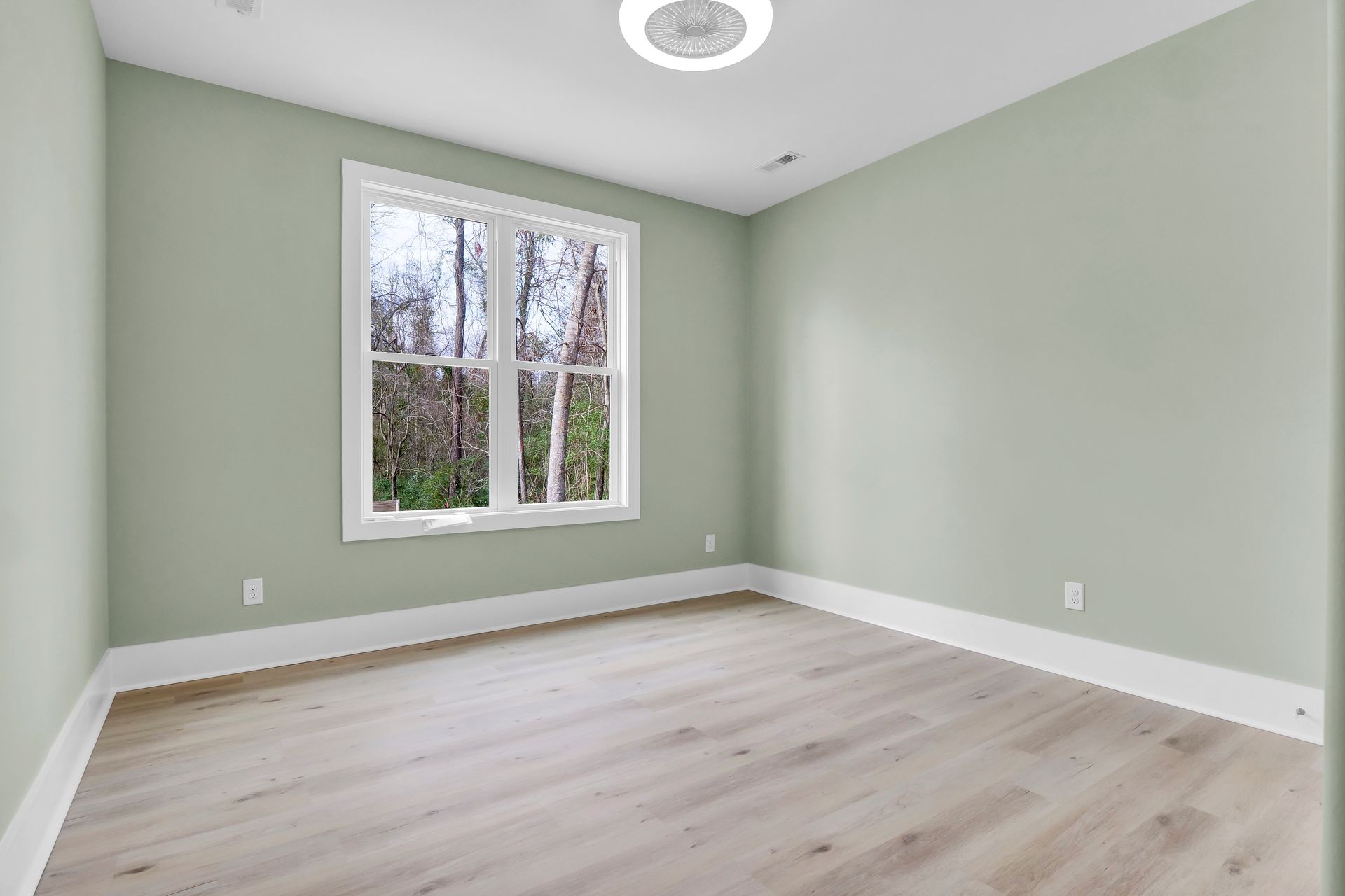 An empty room with a window and a ceiling fan.