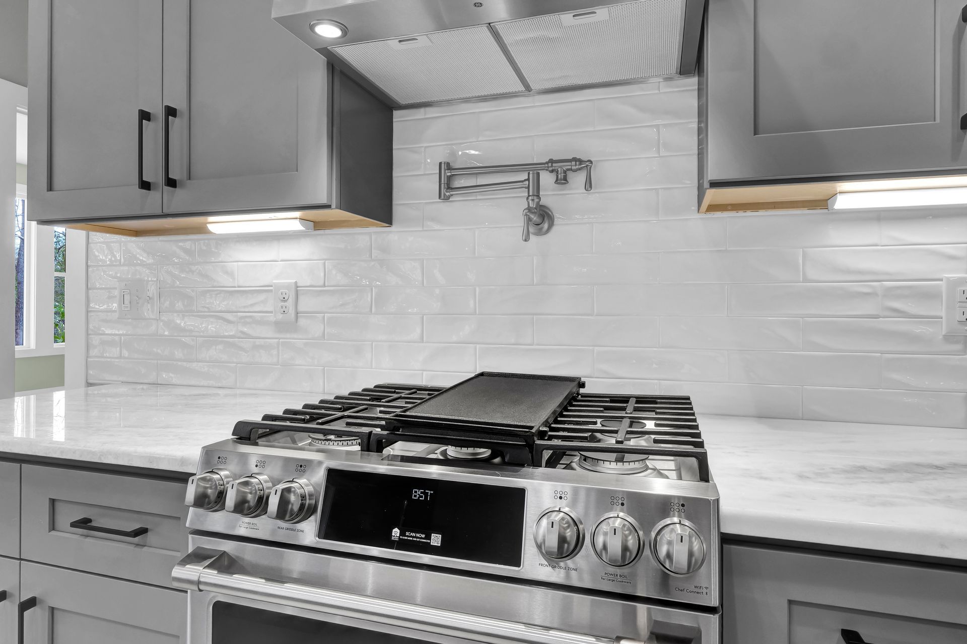 A stainless steel stove top oven is sitting on top of a white counter in a kitchen.
