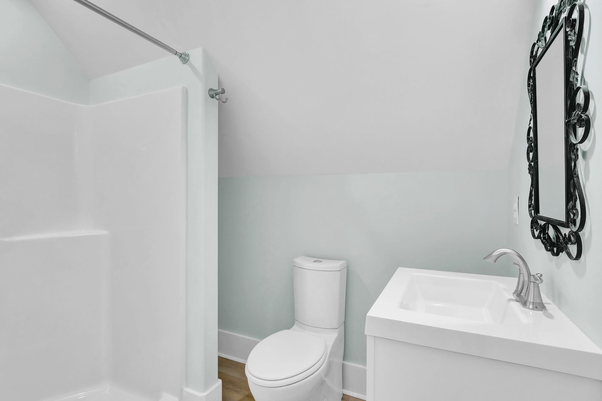 A bathroom with a toilet , sink , shower and mirror.