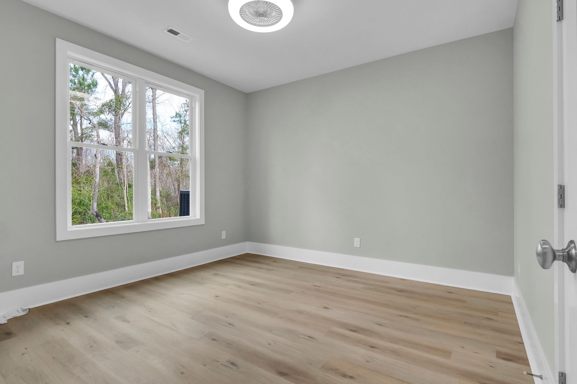 An empty room with hardwood floors and two windows.