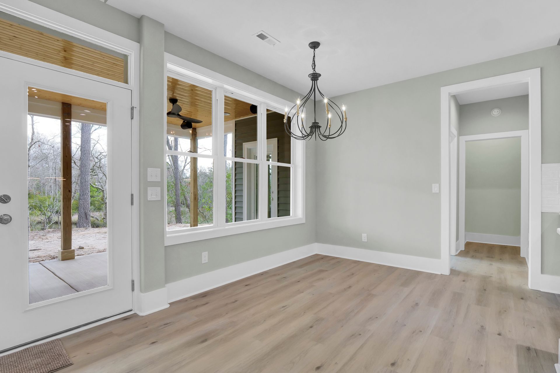 An empty living room with hardwood floors and a chandelier.